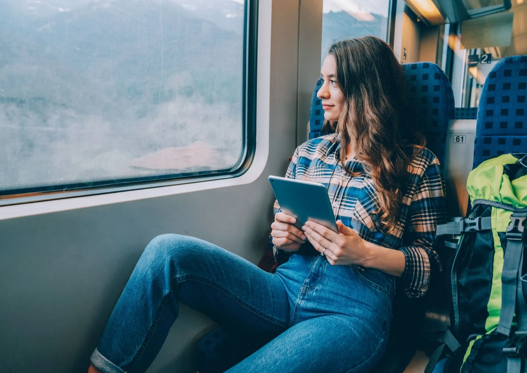 Ragazza con tablet che guarda fuori dal finestrino del treno